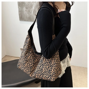 Détail du sac hobo à motif léopard avec bandoulière en cuir noir porté par un mannequin en studio