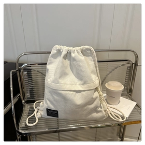 Close-up of white corduroy drawstring backpack with Fashion Instinct label on shelf