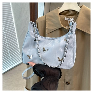 Detail of silver butterfly charms and marble texture on light blue leather tote bag