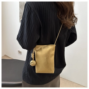 Détail du sac bandoulière doré avec finition métallique élégante et nœud décoratif