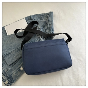 Detail of navy oxford fabric messenger bag with adjustable strap and refined stitching