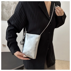 Détail du sac de téléphone argenté métallisé avec texture plissée et nœud sur la bandoulière