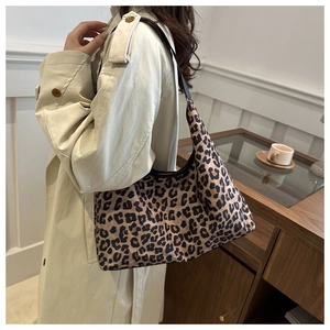 Sac bandoulière à imprimé léopard porté avec un trench beige dans un café élégant