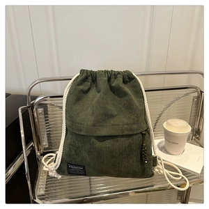 Detail of army green corduroy drawstring backpack with black fashion tag and white rope handle