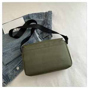 Detailed view of the olive green canvas messenger bag with adjustable black strap on fabric