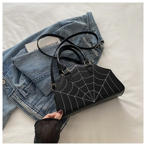 Detail view of gothic black shoulder bag featuring spider web embroidery and gold hardware