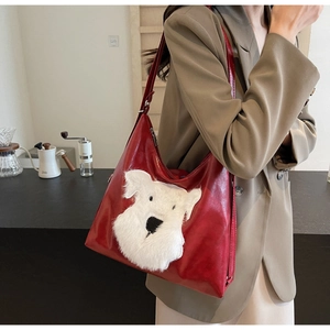 Détail du sac à épaule en cuir rouge avec un motif de chien schnauzer en peluche