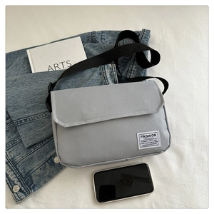 Detail of grey oxford fabric crossbody bag with adjustable strap and brand label