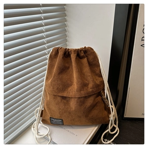 Close-up of brown corduroy drawstring backpack showing ribbed texture and black cloth label