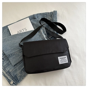 Detail shot of black oxford fabric messenger bag with adjustable strap on white background