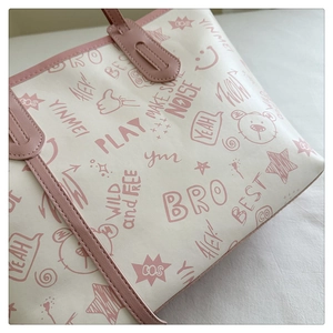 Detailed close-up of pink leather edge and cartoon graffiti prints on a tote bag