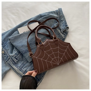 Detail of dark brown leather handbag with unique white spider web stitching and handle