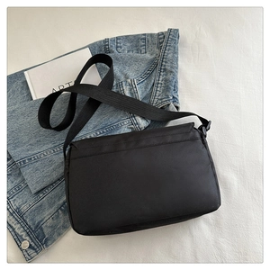 Detail view of black oxford cloth crossbody bag with adjustable strap and flap closure