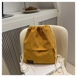 Detail of yellow corduroy drawstring backpack with white cotton straps and fashion label
