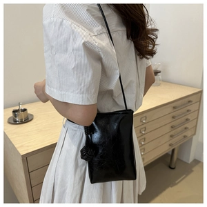 Petit sac bandoulière noir minimaliste avec détail de nœud tressé sur le côté