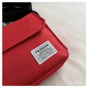 Close-up of red oxford fabric shoulder bag featuring white Fashion Instinct woven label