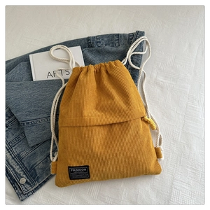 Detailed macro view of yellow corduroy texture and white cotton drawstring on casual backpack
