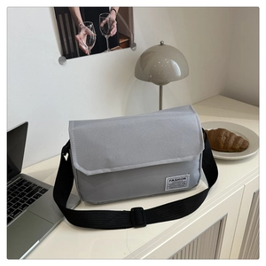Close-up of minimalist grey Oxford fabric messenger bag with adjustable strap and label