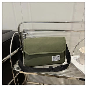 Close-up of military green canvas messenger bag showing stitching and brand label detail