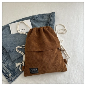 Close-up of brown corduroy drawstring backpack showing textured fabric and fashion label