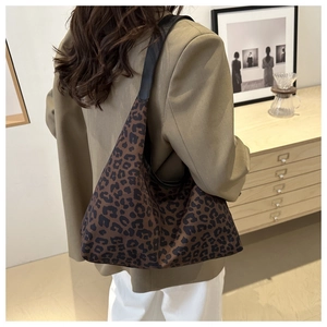 Gros plan d'un sac hobo léopard porté à l'épaule par un mannequin dans un décor de café doux