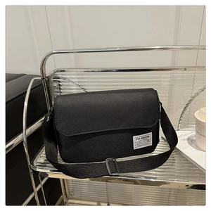 Detail of the black oxford crossbody bag featuring the white Fashion Instinct logo label