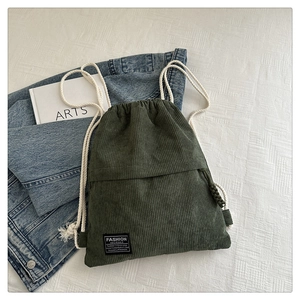 Detailed close-up of dark green corduroy fabric and fashion label on drawstring backpack