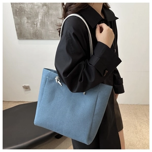Close-up of blue denim tote bag featuring silver knot metal detail on the shoulder strap