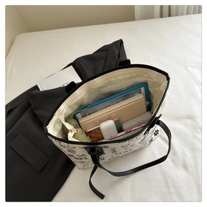 Internal storage detail of contrast tote bag showing iPad, notebook, and daily essentials