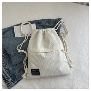 Detail of white corduroy drawstring backpack with Fashion Instinct label on fabric