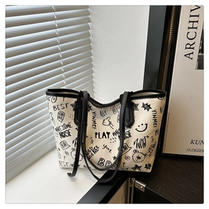 Detailed view of white tote bag featuring black cartoon graffiti and durable twin straps