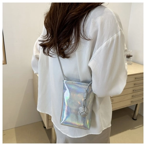 Détail du petit sac à bandoulière holographique argenté avec un pendentif tressé élégant