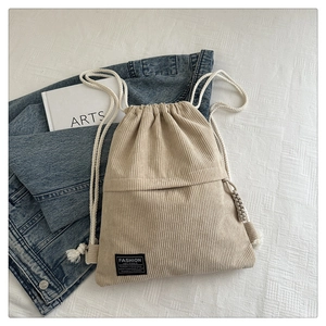 Detail view of khaki corduroy drawstring backpack with fashion label and thick cotton ropes