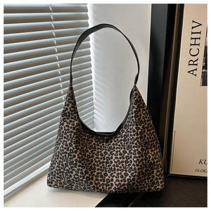 Detail van luipaardprint hobo-tas met slanke zwarte riem op een minimalistische vensterbank