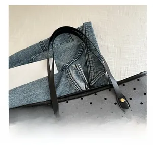 Detailed macro view showing grey polka dot fabric and black leather handles with gold rivets