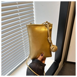 Détail du sac bandoulière doré métallique avec texture craquelée et nœud sphérique