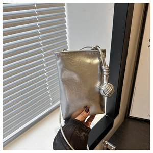 Détail de la pochette téléphone argentée avec un nœud tressé élégant sur la bandoulière
