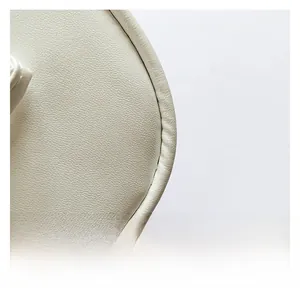 Dettaglio macro della texture in pelle crema e delle cuciture precise sul bordo borsa