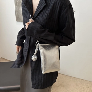 Sac bandoulière argenté métallisé avec détail de nœud porté par un mannequin