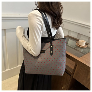 Detailed view of grey canvas tote bag with red heart pattern and black leather strap