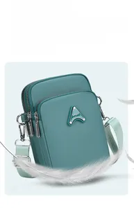 Detailed close-up of blue multi-layer nylon crossbody phone bag with three zippers