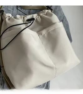 Detail of beige nylon drawstring bucket bag showing front pockets and smooth fabric texture