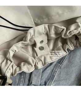 Detail view of the magnetic closure and drawstring on minimalist beige crossbody bucket bag