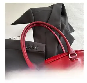 Détail macro de la poignée arrondie confortable sur un sac à main en cuir verni rouge