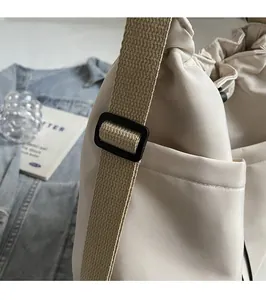 Detail of adjustable strap on a cream crossbody bucket bag with casual urban styling