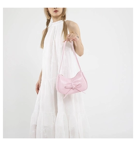 Dettaglio della borsa hobo rosa chiaro con fiocco, portata da modella in pizzo bianco