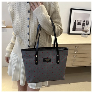 Close-up of gray fabric tote bag with red polka dots and black leather brand label