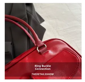 Gros plan d'un sac à main rouge brillant avec anneau métallique argenté et détails du manche