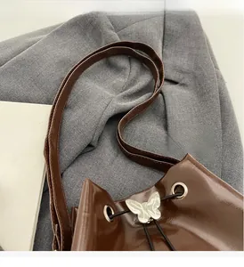 Détail du sac seau en cuir ciré marron foncé avec boucle papillon argentée et cordon de serrage