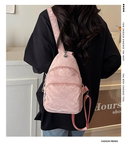 Pink glossy chest bag worn by a model in black outfit, showing back view and straps